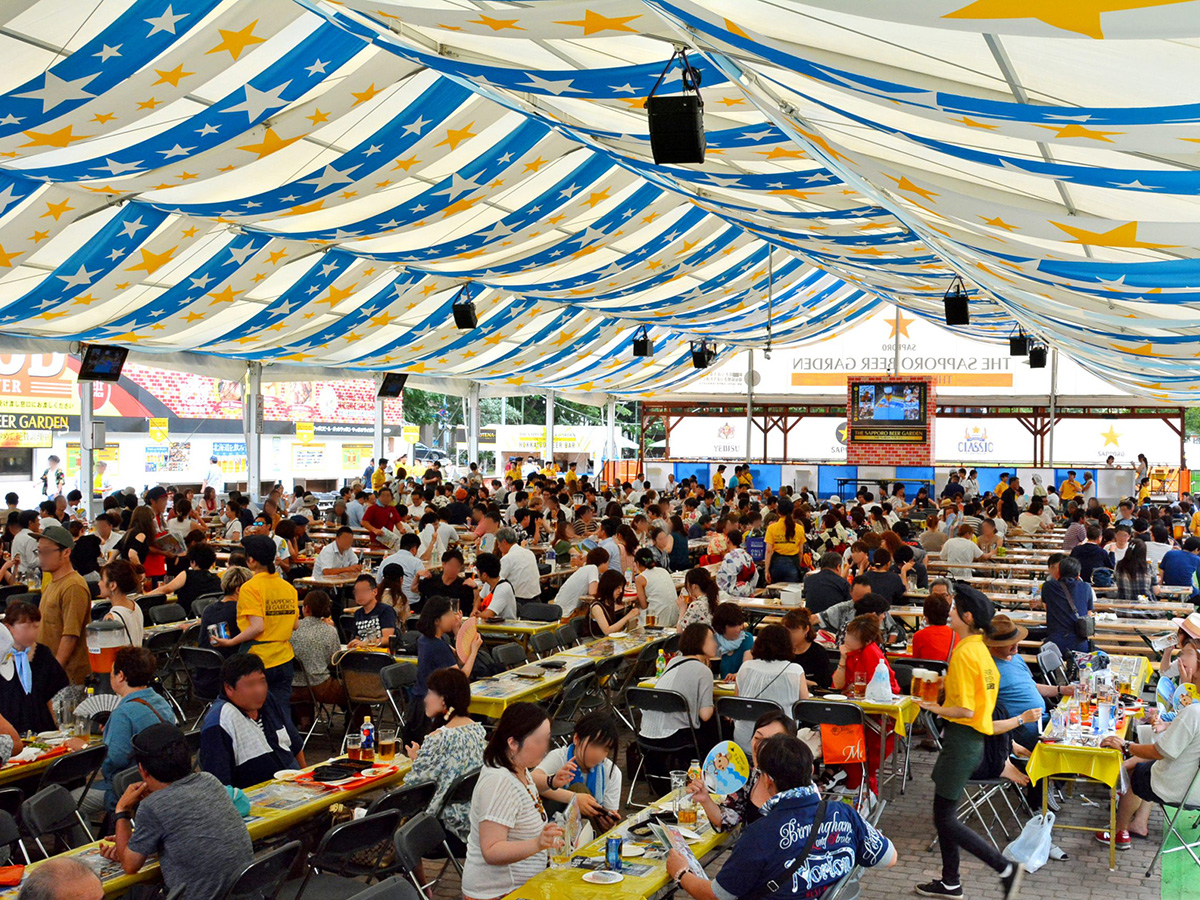 さっぽろ大通ビアガーデンの会場内。テントの下に長テーブルが並べられ、多くの来場者が飲食を楽しむ様子