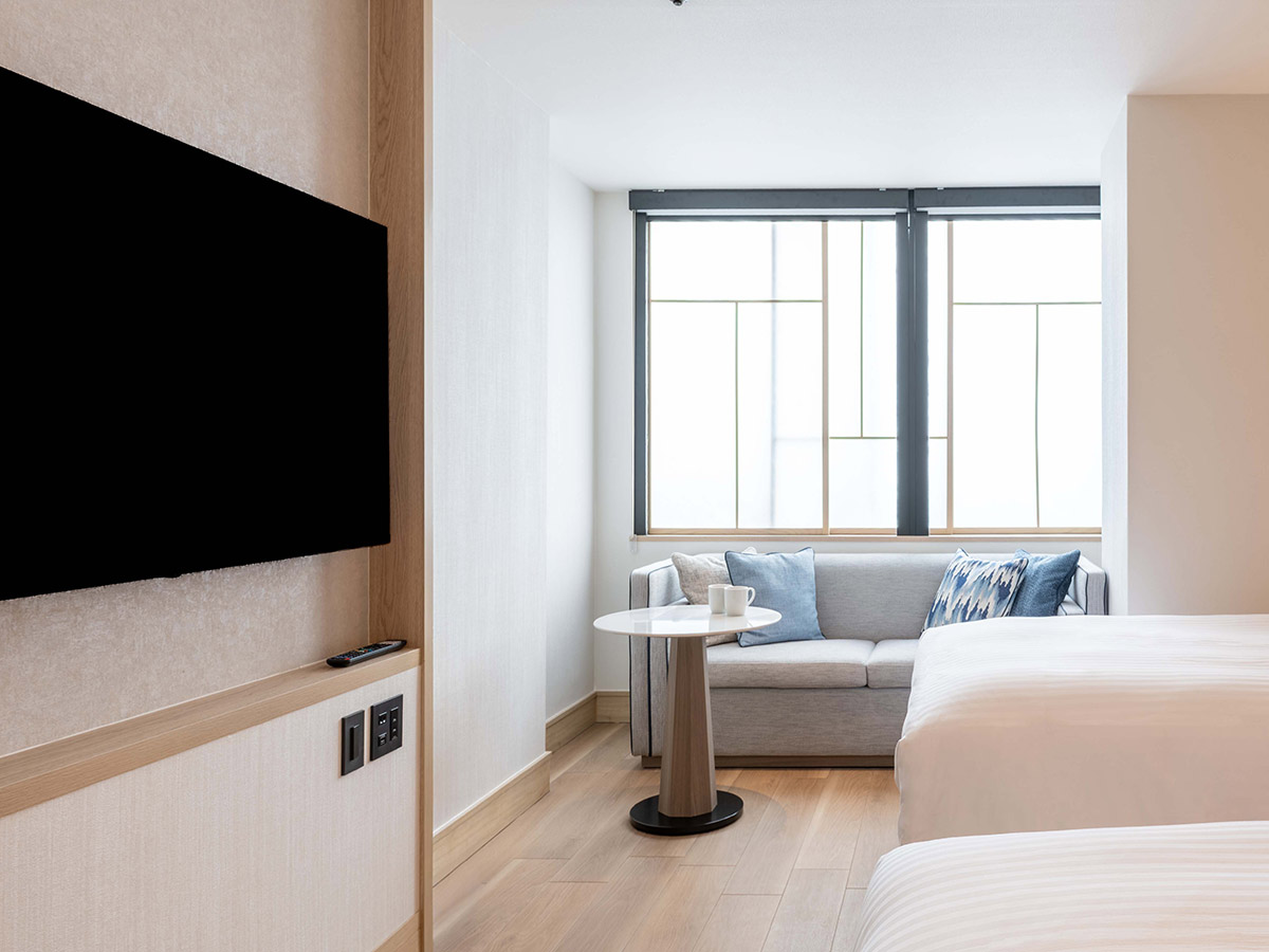 新客室ツインルームのベッドと窓とソファーとテレビ