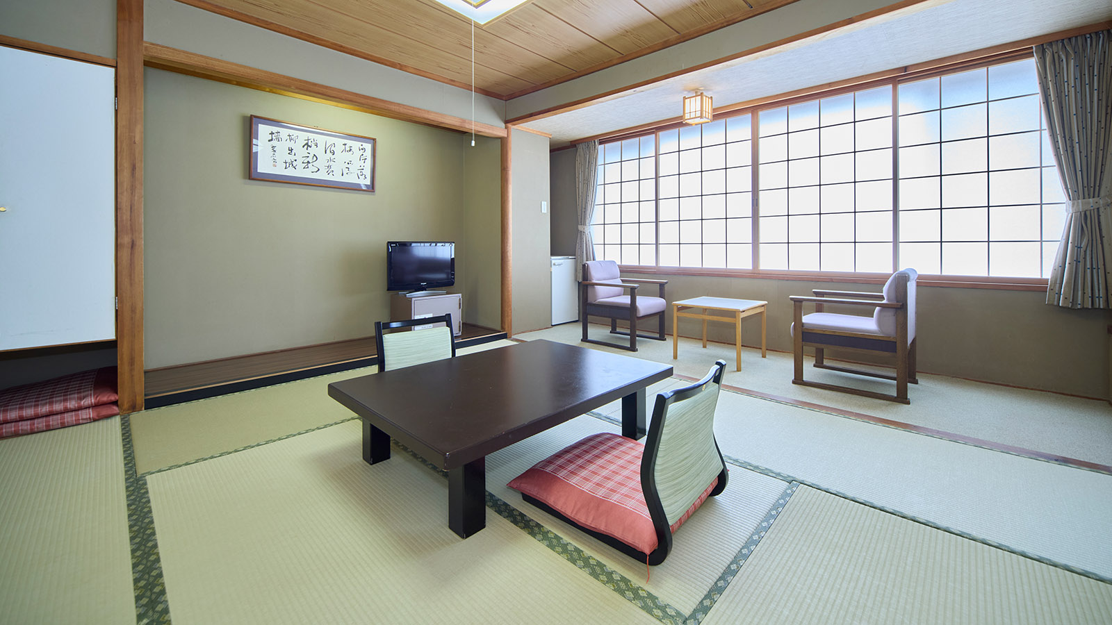 昼の光が入る、鳴子温泉ホテル亀屋の西館・和室8畳の客室。中央の座卓の奥にテレビと習字の額縁がある