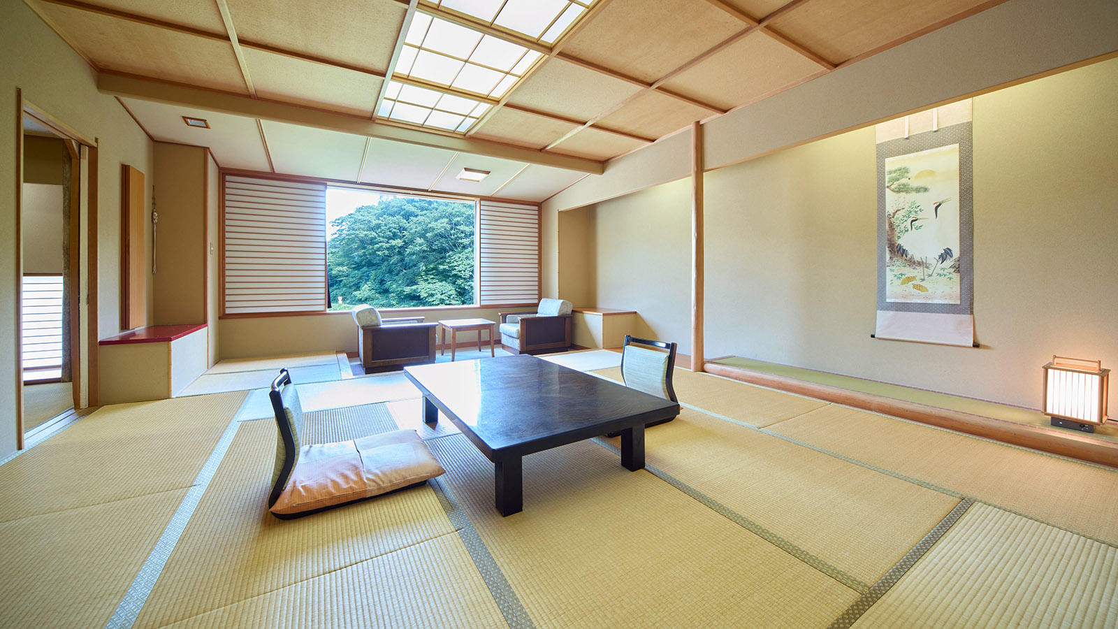 鳴子温泉ホテル亀屋の東館・和室特別室(12.5畳と6畳)。座卓と座椅子、広縁。窓から望む景色